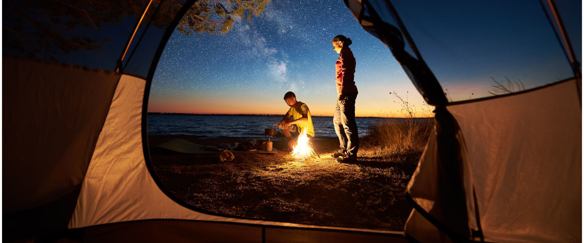 Couple at night campfire outside of camping tent
